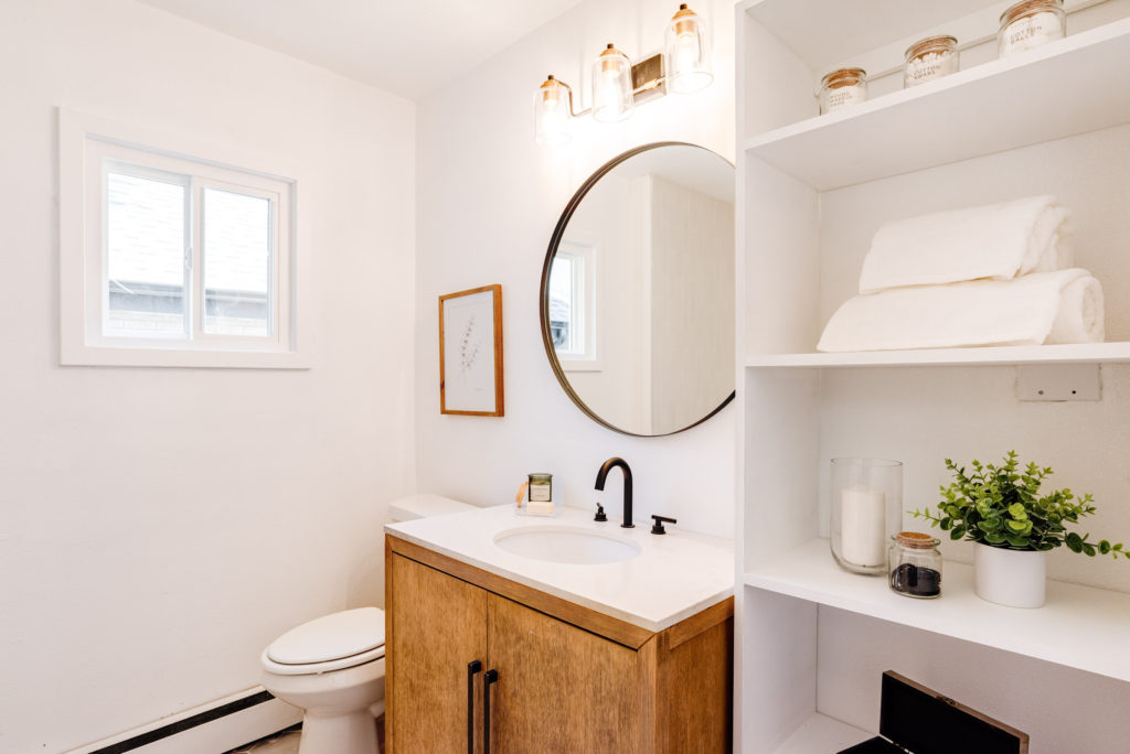 Updated bathroom, open shelving, bathroom storage, round circle mirror, black and brass fixtures

https://www.sagewoodinteriors.com/shop/